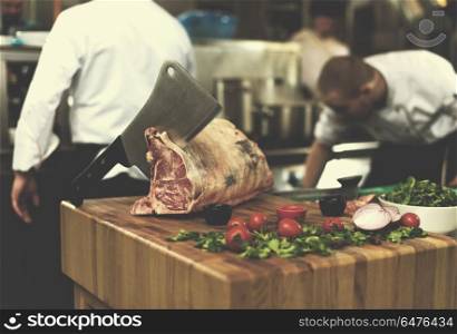 chef using ax while cutting big piece of beef on wooden board in restaurant kitchen. chef cutting big piece of beef