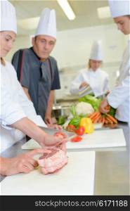 Chef watching student tie joint of meat