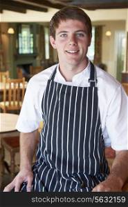 Chef Wearing Whites And Apron Sitting In Restaurant