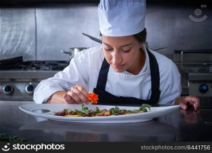 Chef woman garnishing flower in dish at stainless steel kitchen