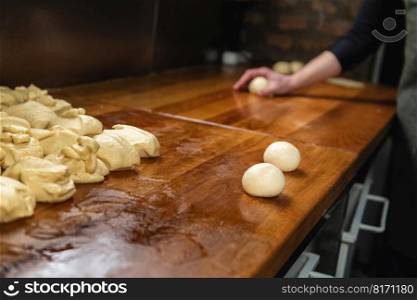 Chefs hand preparing round pieces of dough in a commercial restaurant, kitchen. Chefs Hand Preparing Round Pieces of Dough 
