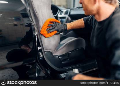 Chemical cleaning of car seats using special agent. Carwash service, male worker in gloves removes dirt. Chemical cleaning of car seats using special agent