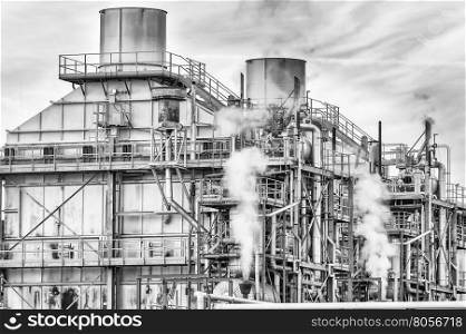 Chemical plant of a factory. Smokestacks ,pipes and tank. Black and white