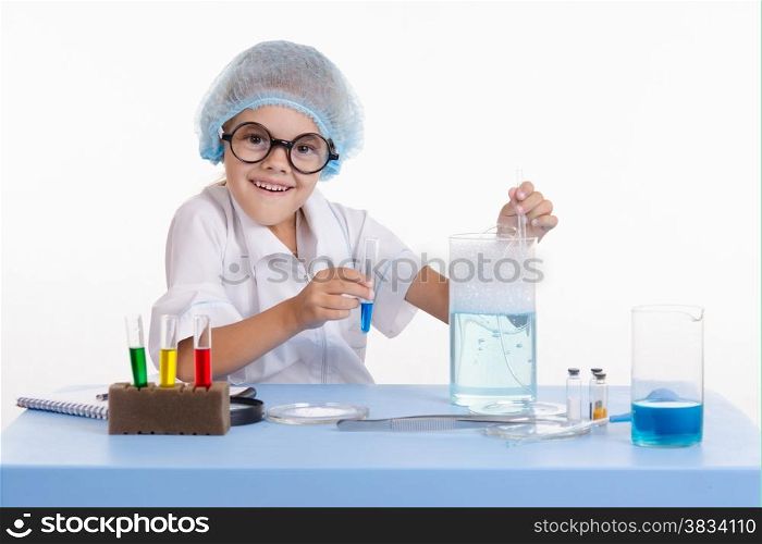 Chemist girl sitting at the table with the reagents in chemistry class and puts experiments