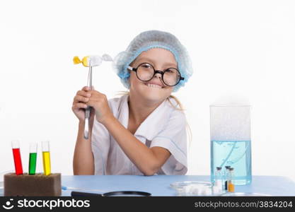 Chemist girl sitting at the table with the reagents in chemistry class and puts experiments