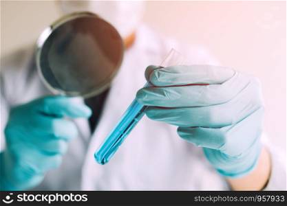 Chemist or scientist using magnifying glass dispense the solution in a glass jar.