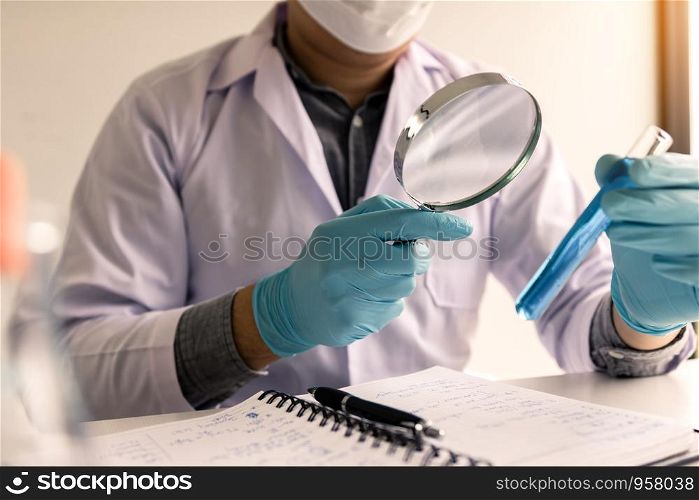 Chemist or scientist using magnifying glass looking the solution in test tube.