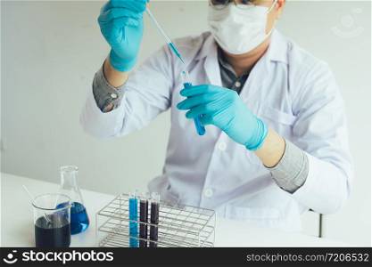 Chemist scientist conducts experiments by synthesising compounds with using dropper in a test tube.
