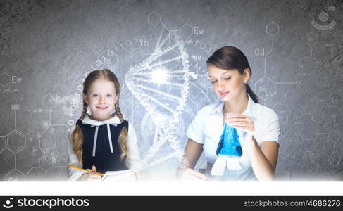 Chemistry lesson. Young teacher and her pupil doing tests at chemistry lesson