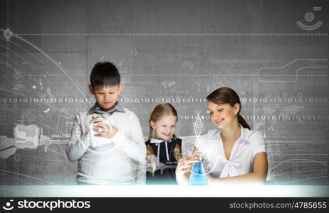 Chemistry lesson. Young teacher and her pupils doing tests at chemistry lesson