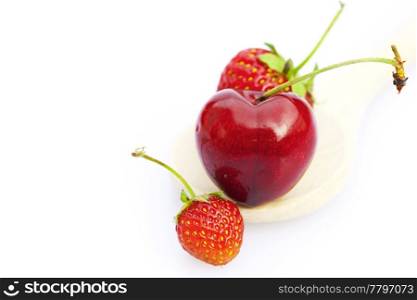 cherry and strawberry in a wooden spoon isolated on white