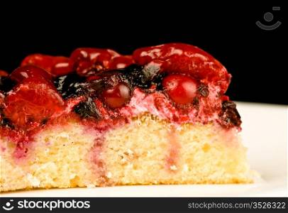cherry cake on white dish, black background