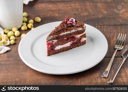 Cherry cake on white porcelain plate on wooden table