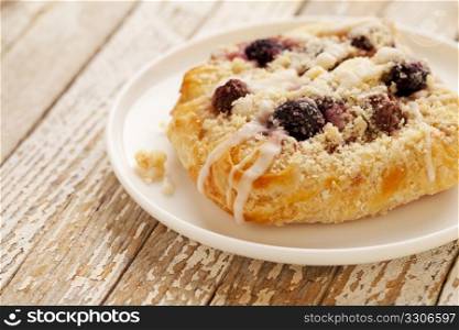 cherry cheese danish pastry on white plate against grunge wood table