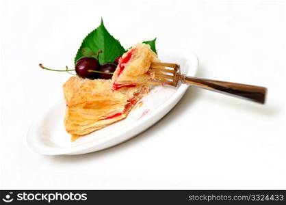 Cherry filled flakey turnover on a white plate with fresh cherries on the side.. Fruit Turnover