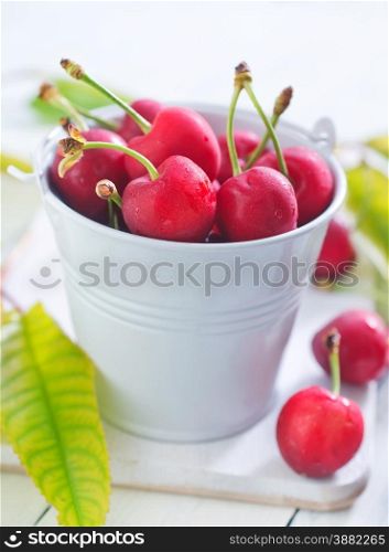 cherry fruits in white bucket and on a table