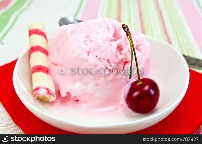 Cherry ice cream in a bowl with wafer rolls on a red paper napkin, spoon on a background of a linen tablecloth