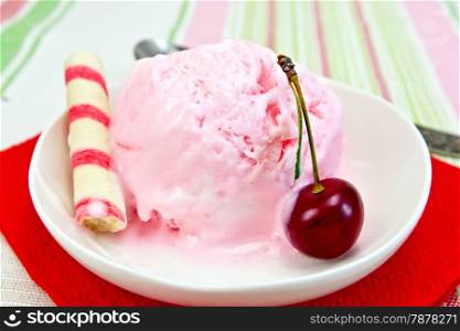 Cherry ice cream in a bowl with wafer rolls on a red paper napkin, spoon on a background of a linen tablecloth