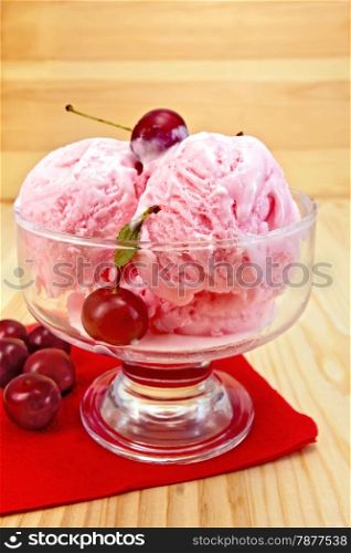 Cherry ice cream in a glass bowl with berries on red paper napkin on a wooden boards background