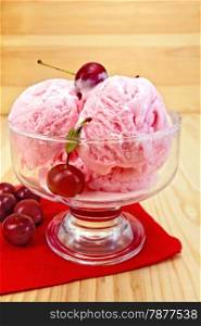 Cherry ice cream in a glass bowl with berries on red paper napkin on a wooden boards background