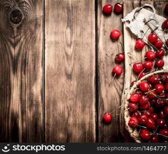 Cherry in a basket on the Board and metal tool for cherries. On a wooden table.. Cherry in a basket on the Board