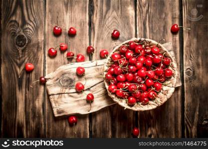 Cherry in a basket on the old Board. On a wooden table.. Cherry in a basket on the old Board.