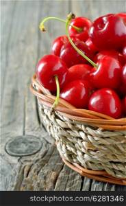 cherry in straw basket isolated on old wooden background