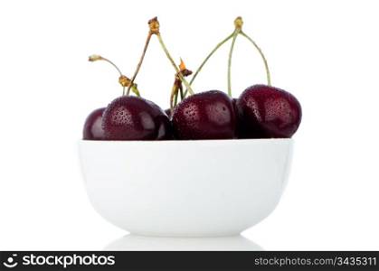 Cherry in white bowl on white reflective background.