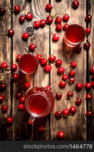 Cherry juice in jug and glasses. On wooden background.. Cherry juice in jug and glasses.