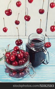 Cherry juice with glass of berries. Cherry juice with glass jar of berries on blue wooden background