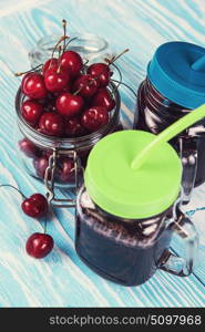 Cherry juice with glass of berries. Cherry juice with glass jar of berries on blue wooden background