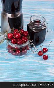 Cherry juice with glass of berries. Cherry juice with glass jar,of berries, blender and juice on blue wooden background