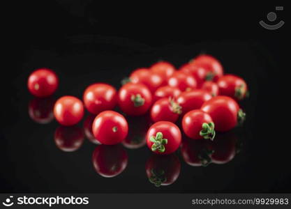 Cherry tomato on a black reflective background . Cherry Tomato on a Black Reflective Background