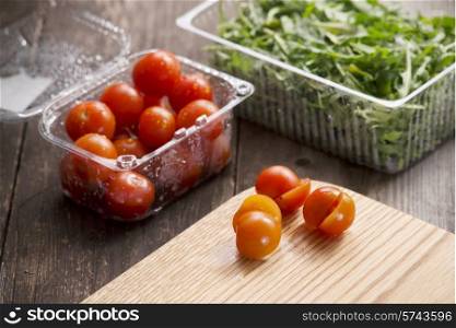cherry tomatoes in plastic dishes and arugula
