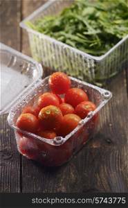 cherry tomatoes in plastic dishes and arugula