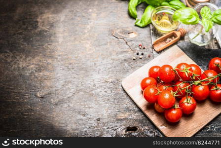 Cherry tomatoes oil and basil leaves on dark wooden background. Ingredients for italian food cooking.