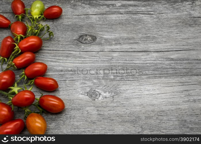 Cherry tomatoes on a gray wooden table. Vegetable border.