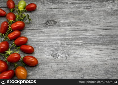 Cherry tomatoes on a gray wooden table. Vegetable border.