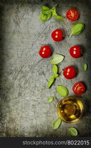 Cherry tomatoes with basil leaves and olive oil on rustic background