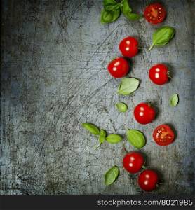 Cherry tomatoes with basil leaves on rustic background