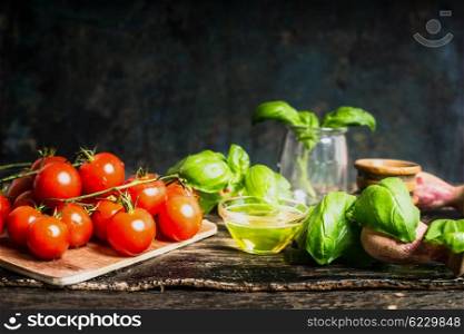 Cherry tomatoes with olives oil and basil on rustic kitchen table on dark background