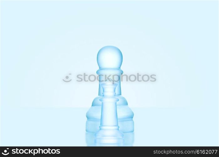 Chess game concept of a single icy frosted pawn standing alone on glacial chessboard.