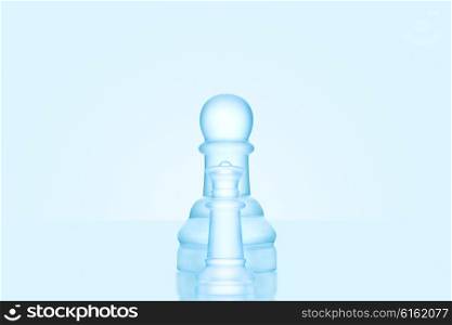 Chess game concept of a single icy frosted pawn standing alone on glacial chessboard.