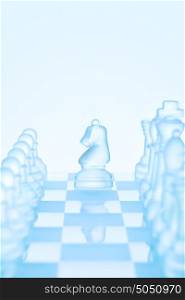 Chess game concept of an icy frosted chess knight standing among chess pieces on glacial chessboard ready for making an L-shaped move.
