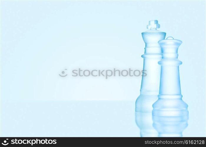 Chess game concept of icy frosted king and queen, the most powerful figures standing together on glacial chessboard.