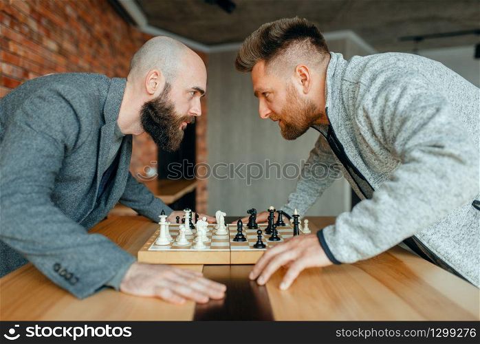 Chess players look into each other&rsquo;s eyes. Two chessplayers finished intellectual tournament indoors. Chessboard on wooden table. Chess players look into each other&rsquo;s eyes