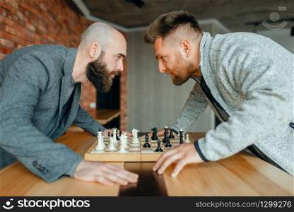 Chess players look into each other&rsquo;s eyes. Two chessplayers finished intellectual tournament indoors. Chessboard on wooden table. Chess players look into each other&rsquo;s eyes