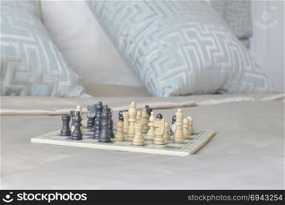 Chess set on satin bedding with light blue pillows in background