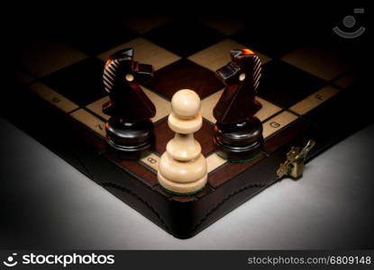 Chessmen on a chess board. A dark background and art illumination.