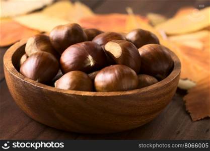 Chestnuts in wooden bowl, photographed with natural light (Selective Focus, Focus on the front of the chestnuts on the top)